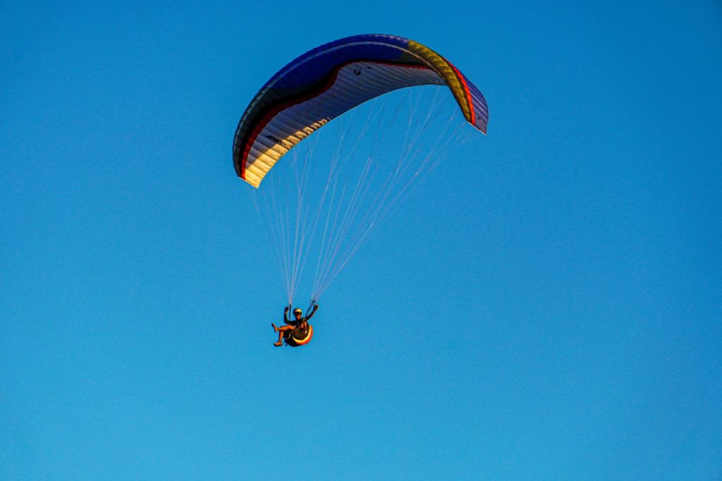 An exhilarating paragliding experience against a bright blue sky, capturing the thrill of flight and adventure.