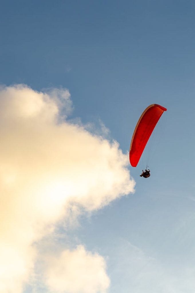 A lone paraglider with a red parachute glides gracefully against a picturesque sky in Brazil.